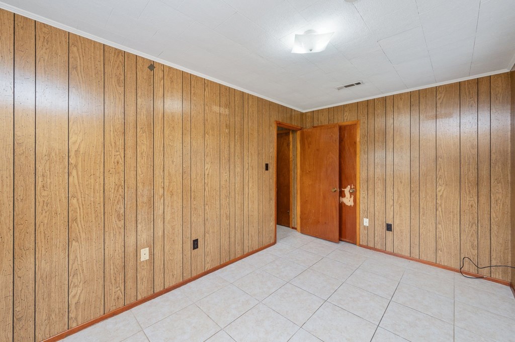 the living room has wood paneled walls and a white tile floor