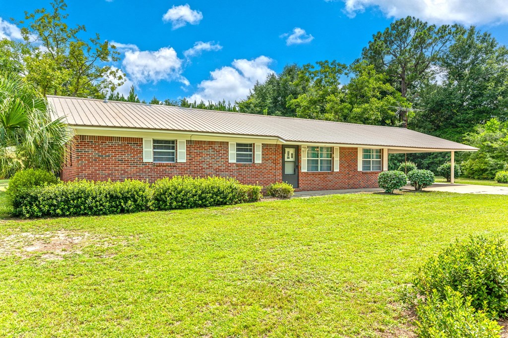 a brick house with green grass and trees