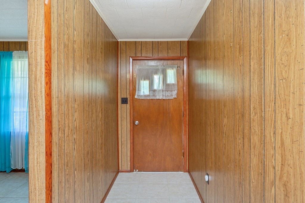 an empty hallway with a wooden door and a tile floor