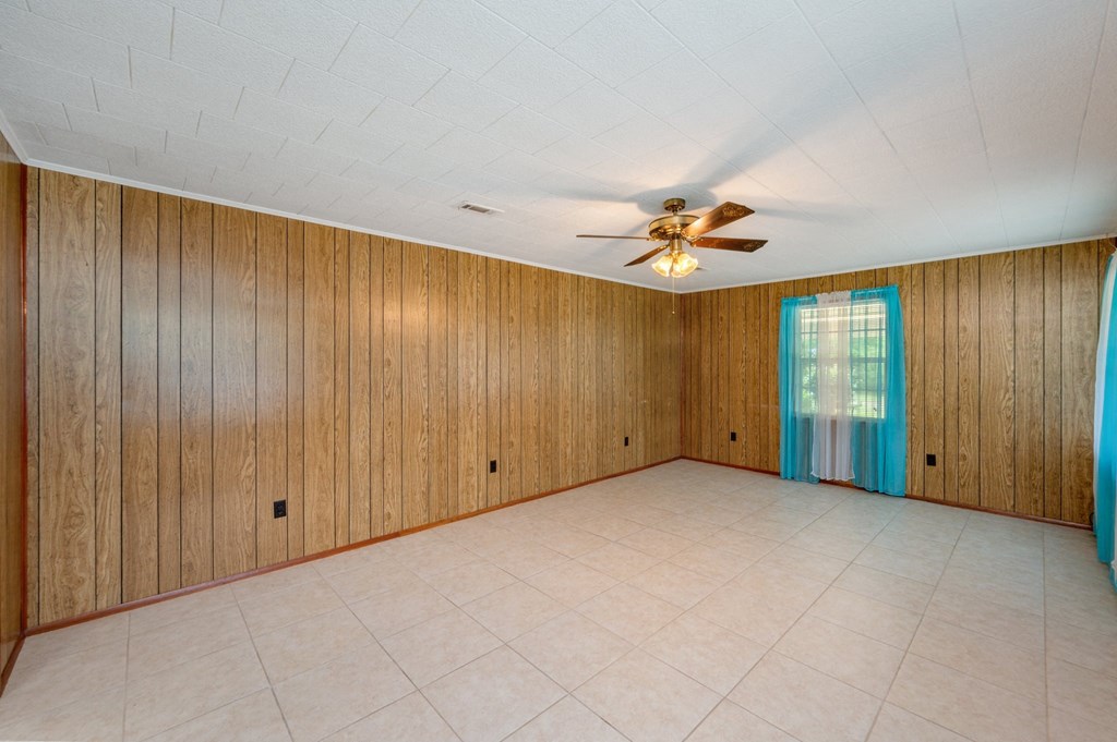 an empty living room with wood paneling and a ceiling fan