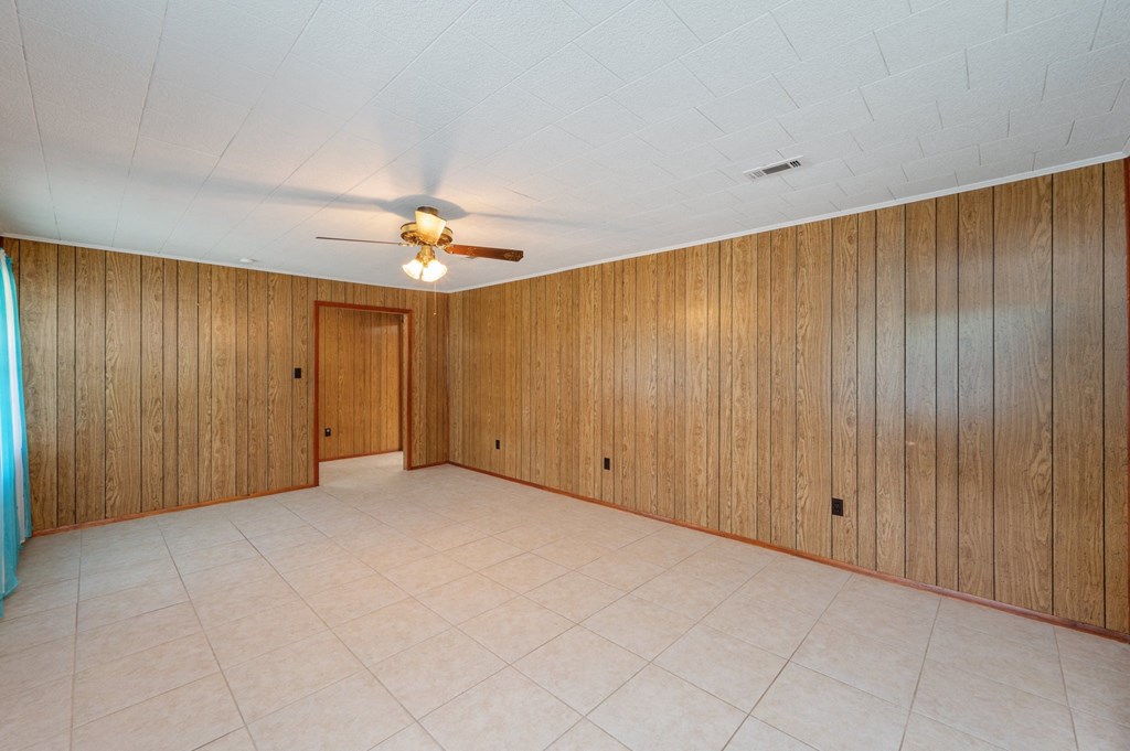 an empty living room with wood paneling and a ceiling fan