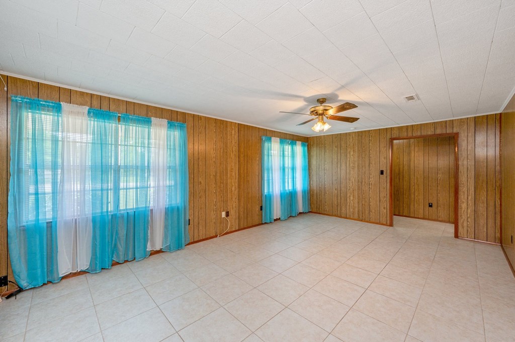 an empty living room with curtains and a ceiling fan