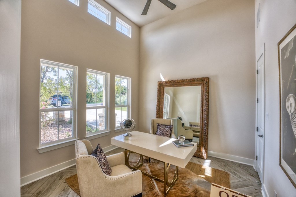 a home office with a desk and chairs and a mirror