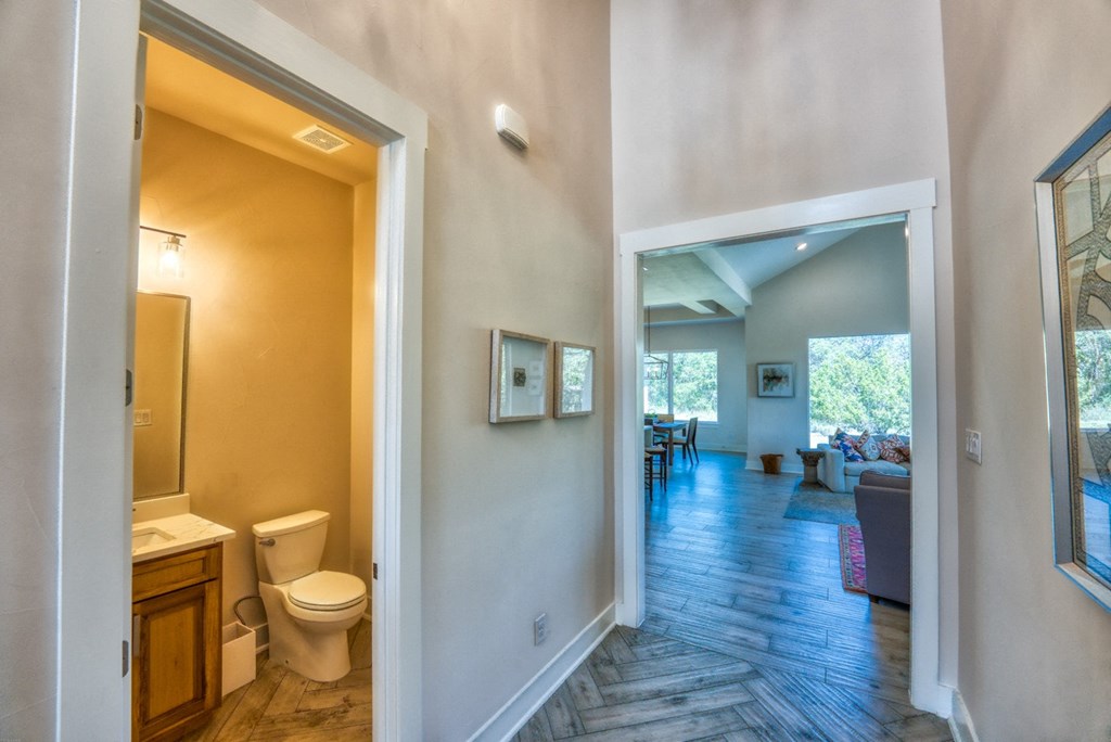 a bathroom with a toilet and a hallway to a living room