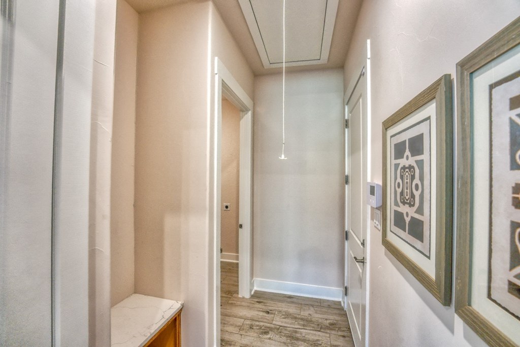 a hallway with framed pictures on the wall and a door leading to a bathroom