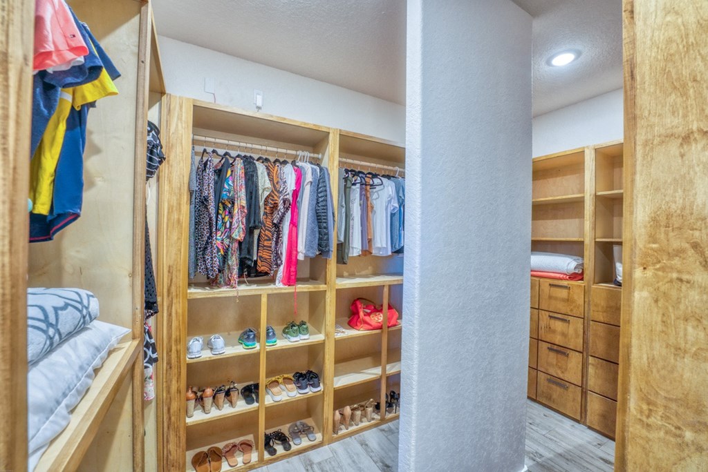 a closet with a lot of shelves and a bed in it