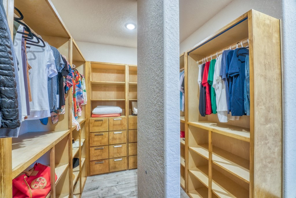 a walk in closet with wooden shelves and racks of clothes