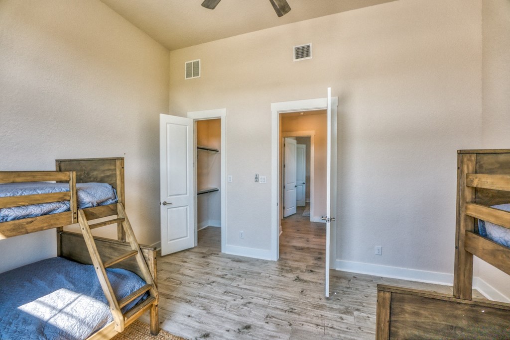a bedroom with bunk beds and a hall to a bathroom