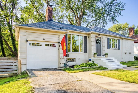 A white house with a black roof and a flag on the front.