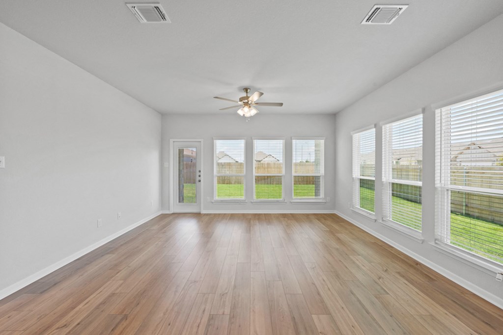 an empty living room with windows and a ceiling fan