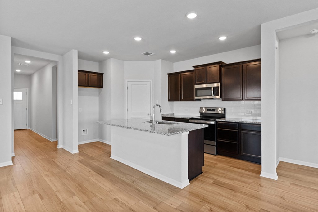 an empty kitchen with a marble counter top and black appliances