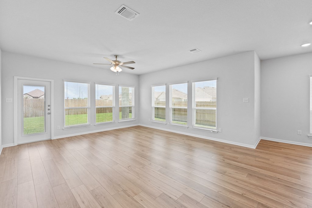 an empty living room with windows and a ceiling fan