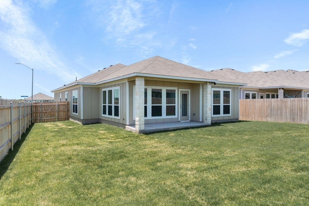 the back of a house with a yard and a fence