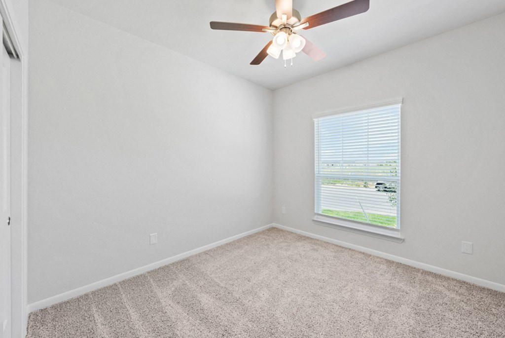 an empty bedroom with a ceiling fan and a window