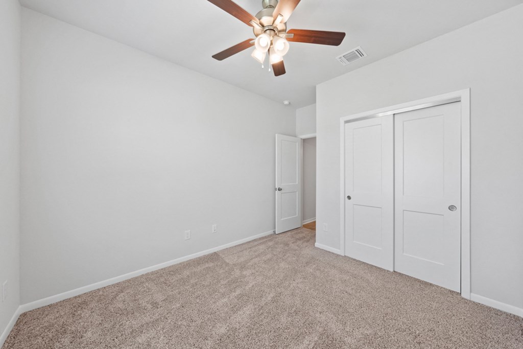 a bedroom with white walls and a ceiling fan