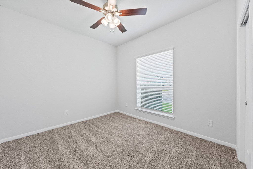 an empty room with a ceiling fan and a window