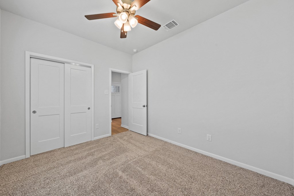 the living room of an empty home with a ceiling fan