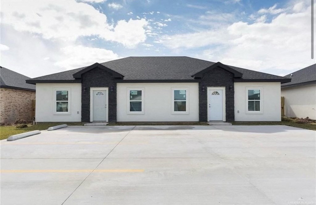 the front of a white and black building with a driveway