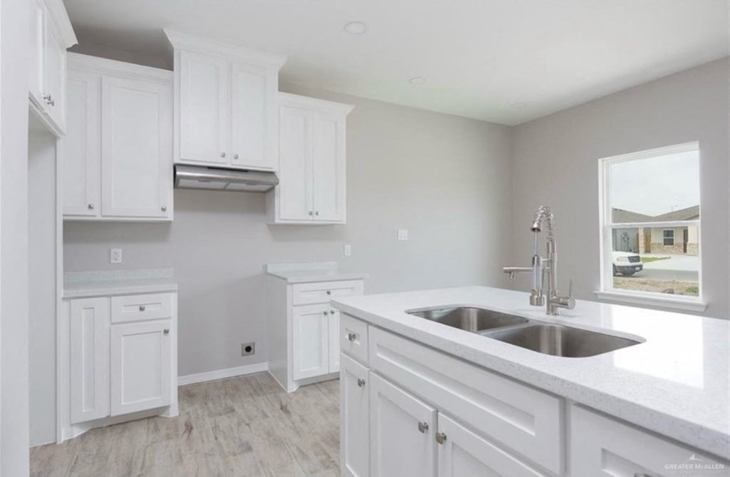 a white kitchen with a sink and a window