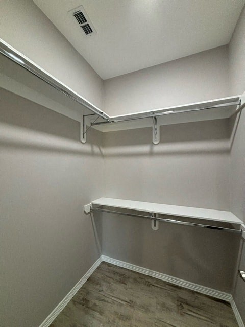 a walk in closet with a mirrored wall and a shelf