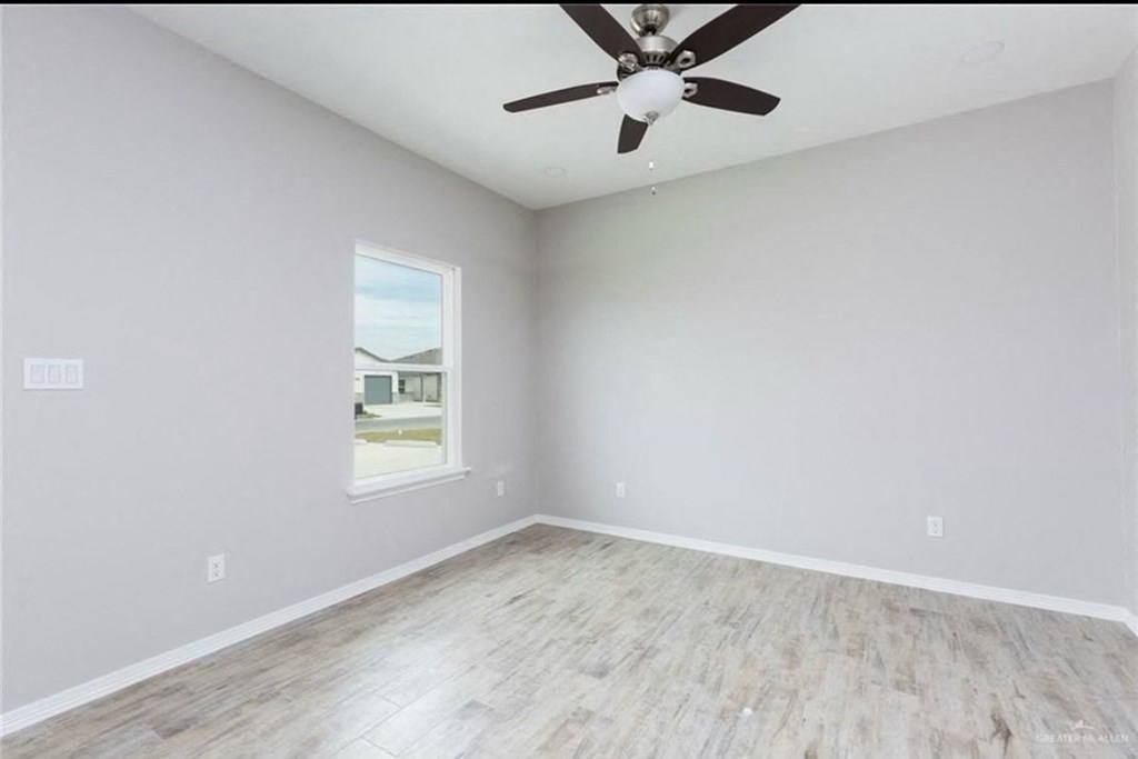 an empty living room with a ceiling fan and a window