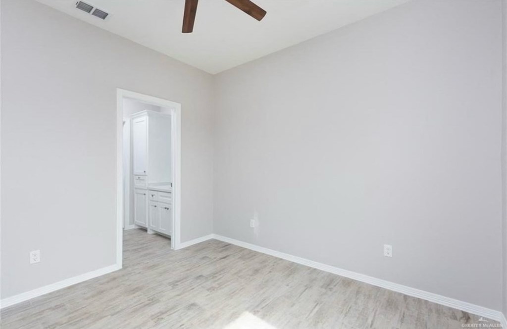 an empty room with white walls and a ceiling fan