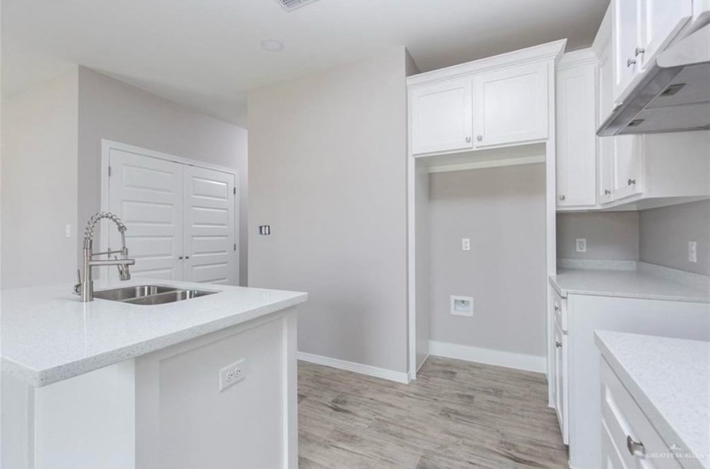 an empty kitchen with white cabinets and a sink