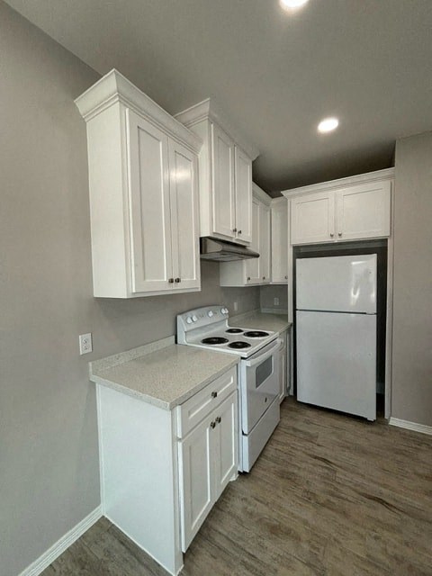 a kitchen with white cabinets and a white refrigerator