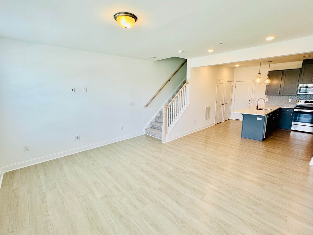 a kitchen and living room with a hardwood floor and a staircase