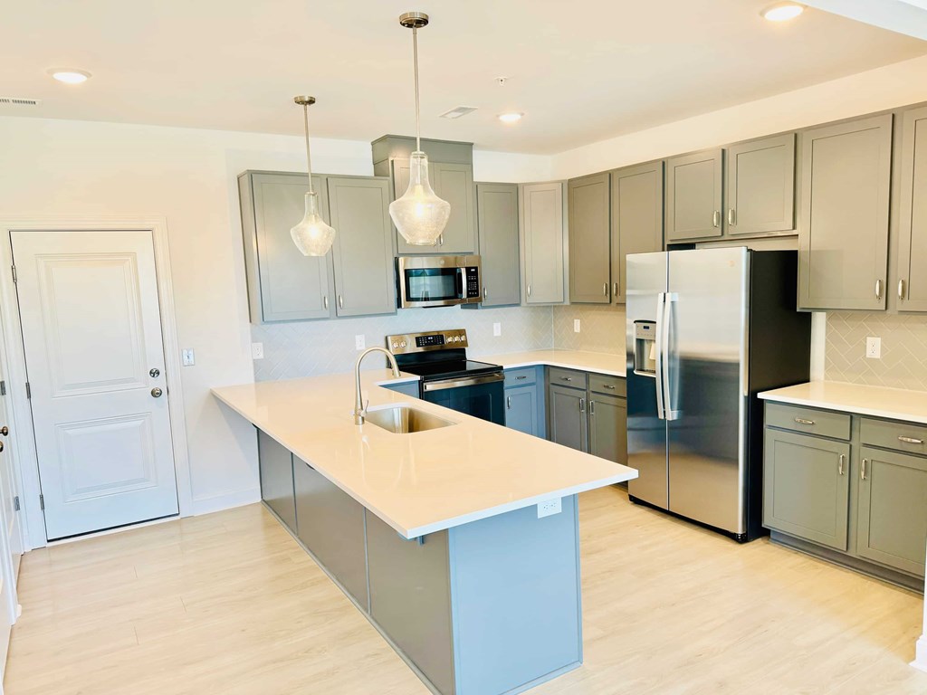 a large kitchen with stainless steel appliances and white counter tops