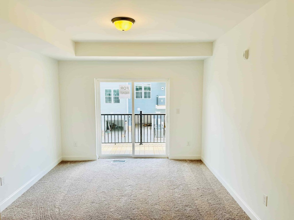 an empty living room with a door to a balcony