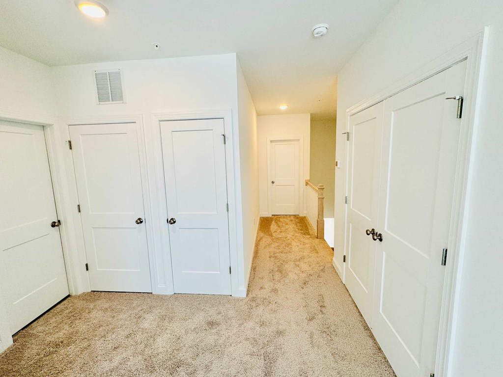 a bedroom with white closets and a carpeted floor