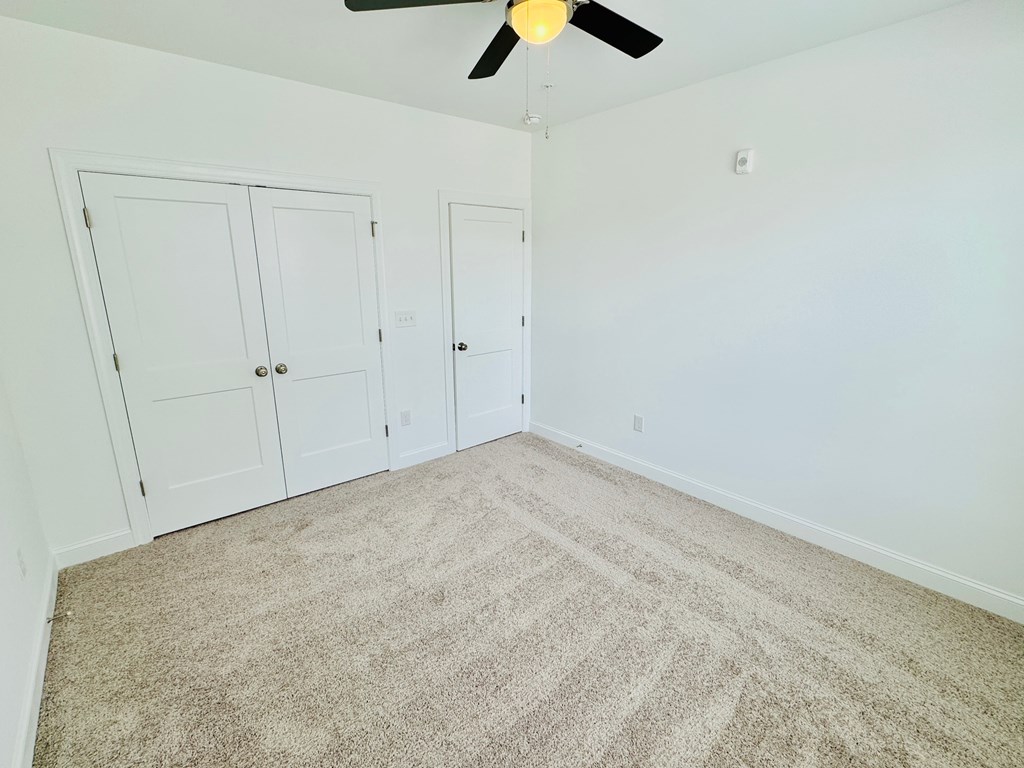 an empty room with carpet and a ceiling fan