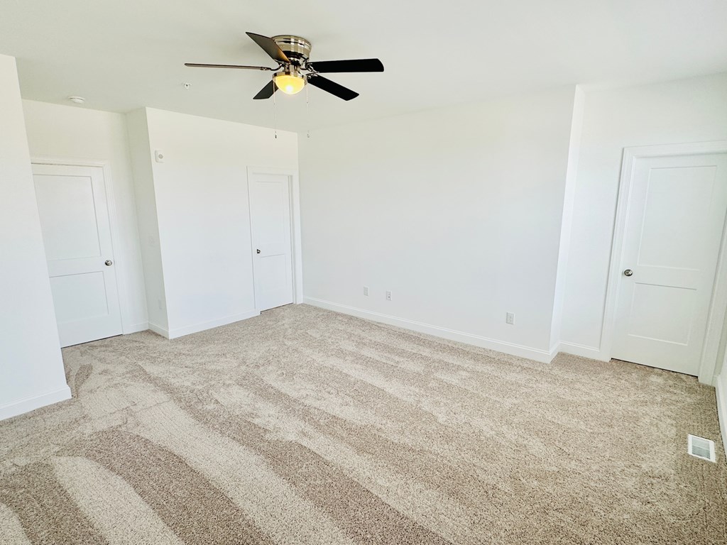an empty room with carpet and a ceiling fan