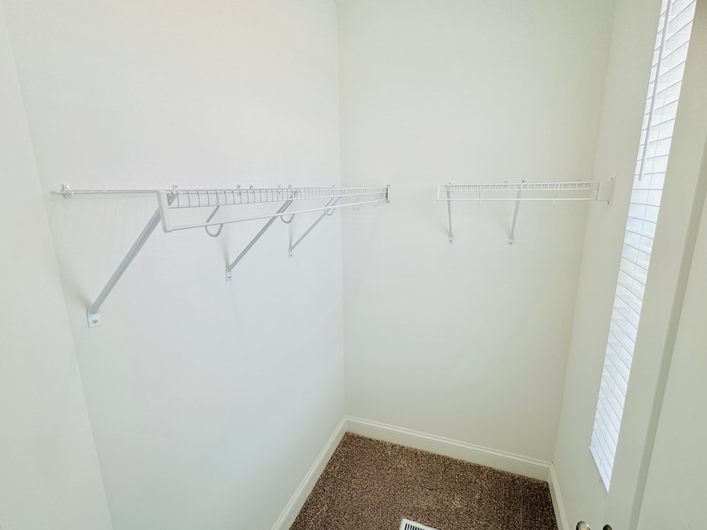 an empty closet with three hanging racks on the wall