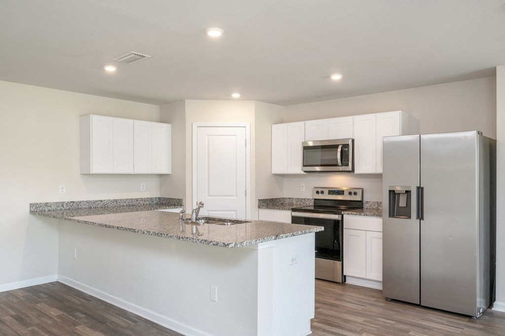 an empty kitchen with an island and stainless steel refrigerator