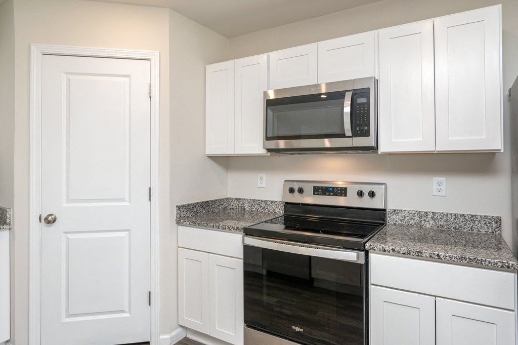 a kitchen with white cabinets and a stove and a microwave