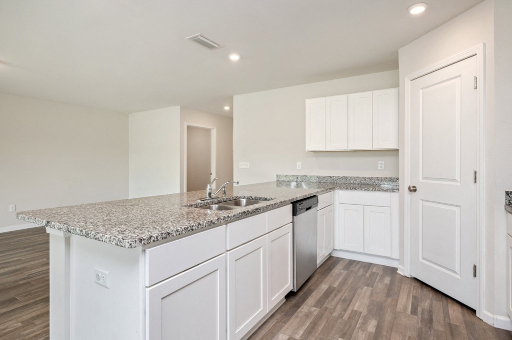 an empty kitchen with white cabinets and a counter top