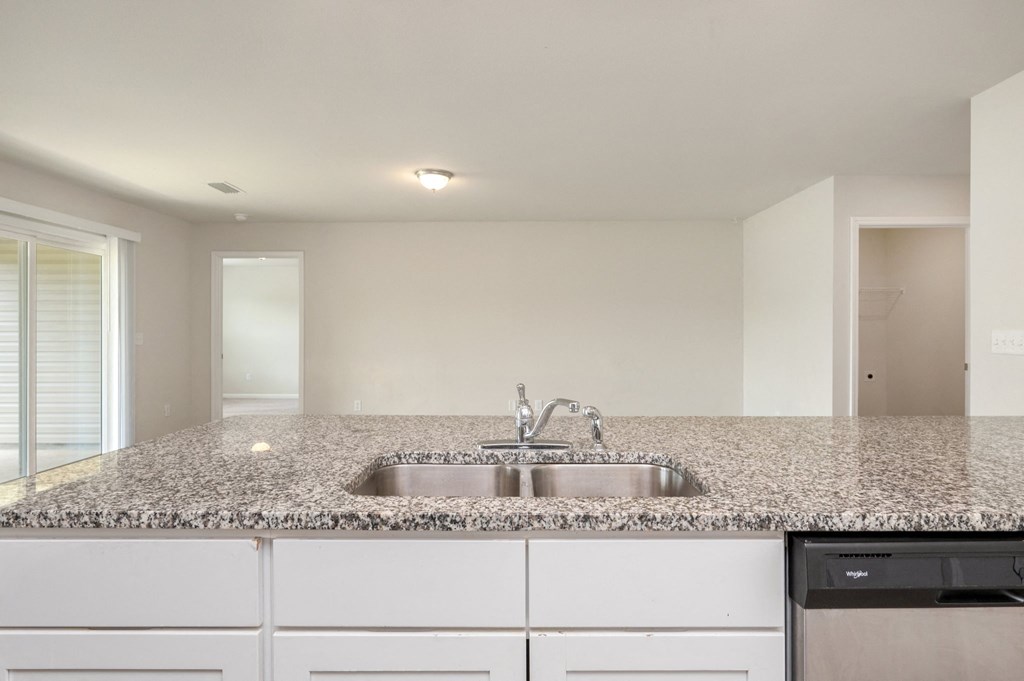 a kitchen with white cabinets and granite counter top and a sink