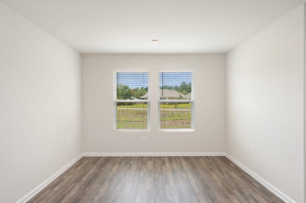 the living room of an empty house with wood floors and two windows