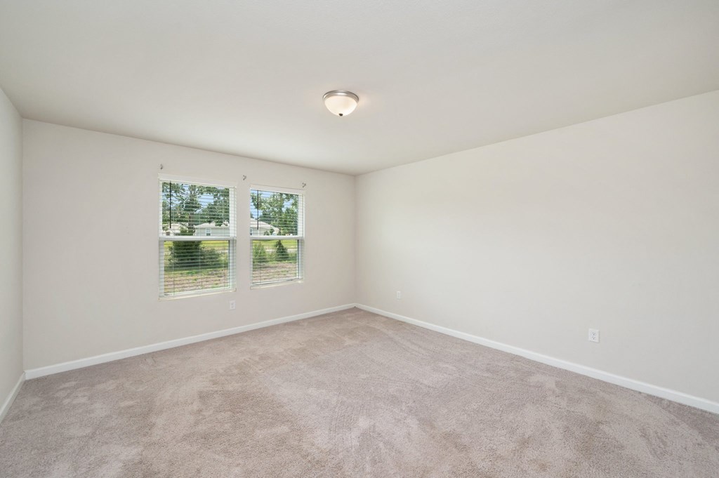 an empty living room with carpet and two windows