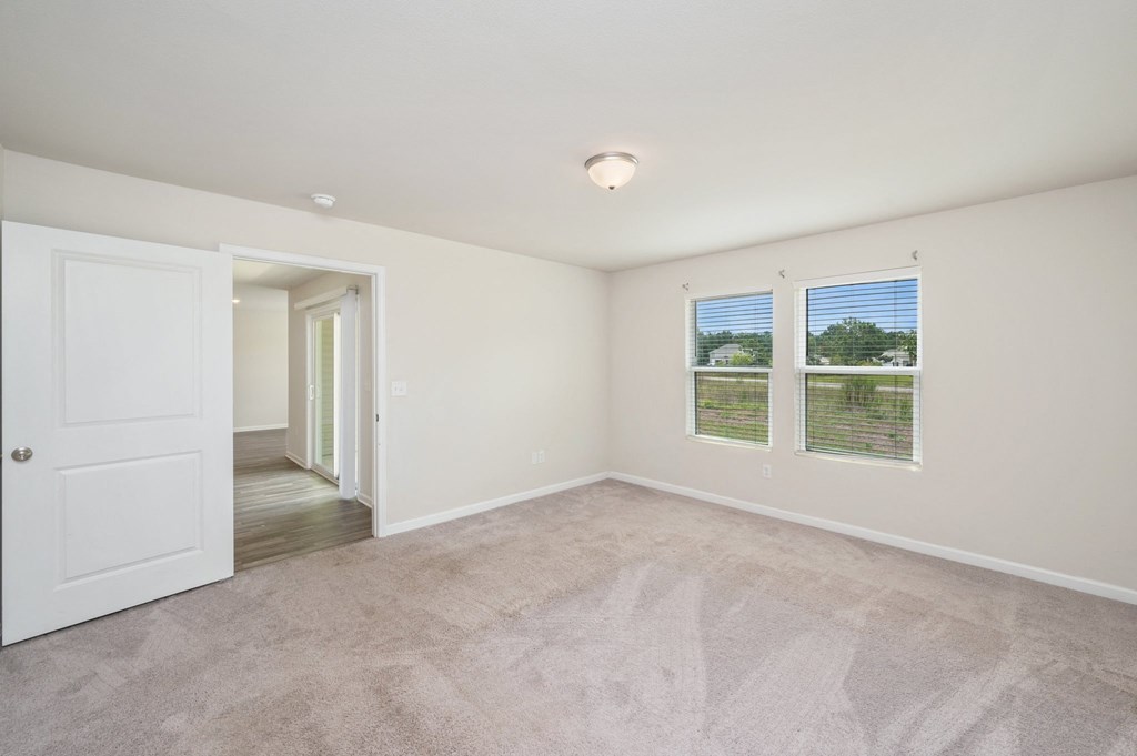 an empty living room with two windows and a door to a hallway