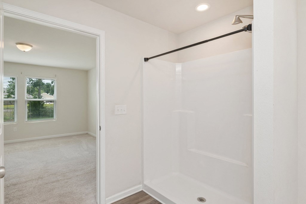 an empty bathroom with a shower and a window