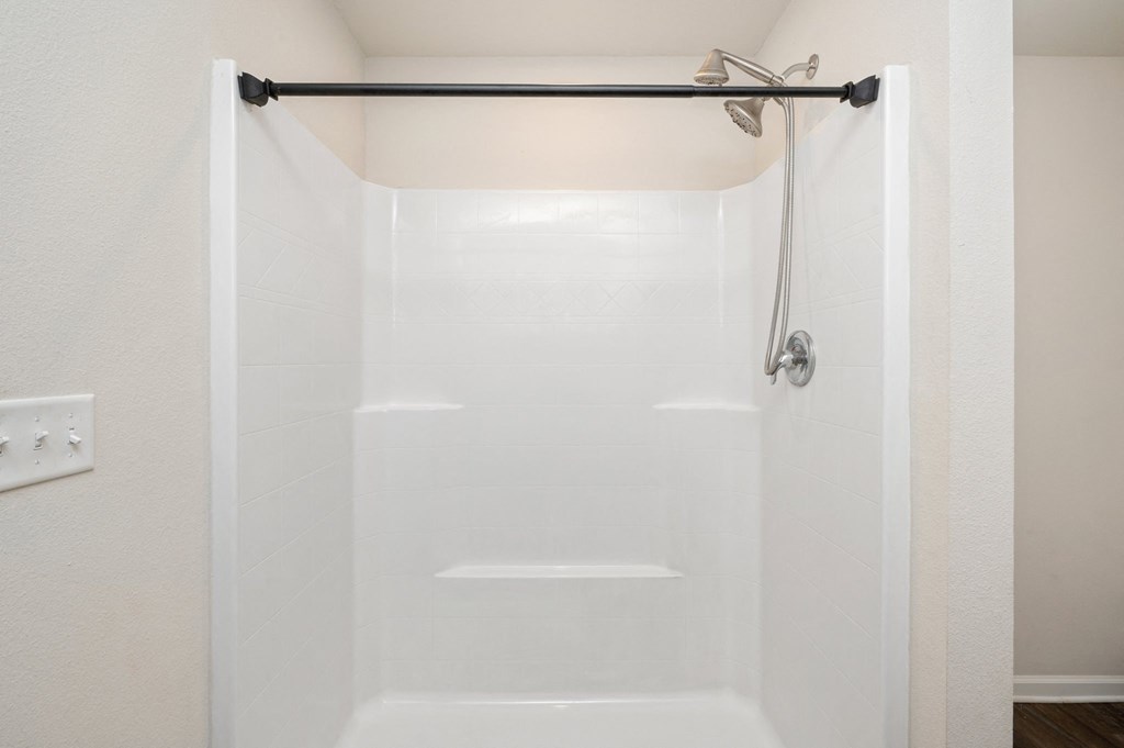 a white shower in a bathroom with a shower curtain