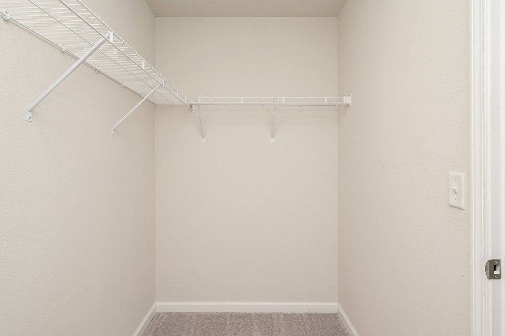 an empty closet in a bedroom with white walls and a white rack on the ceiling