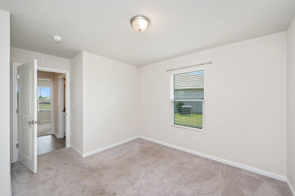 an empty living room with a window and a door to a hallway