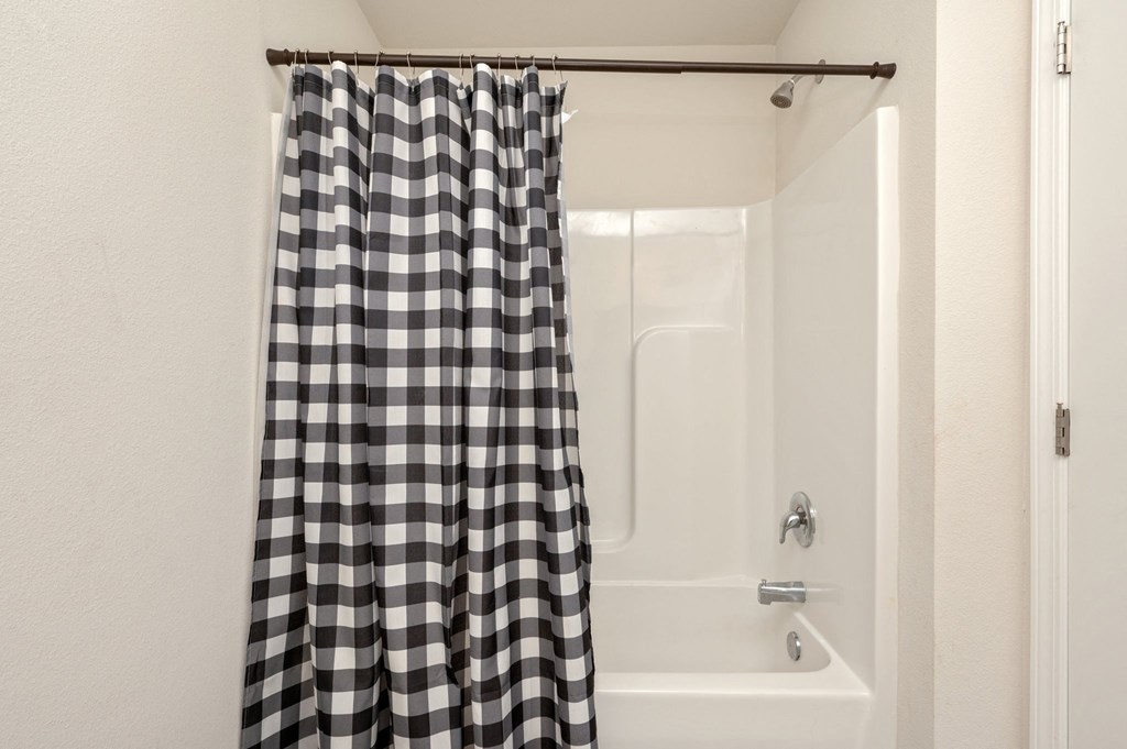 a bathroom with a shower and a black and white shower curtain