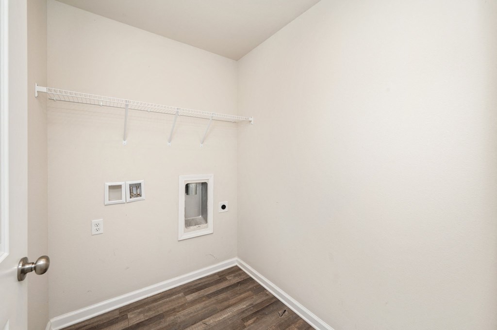 a bedroom with white walls and wood flooring and a closet