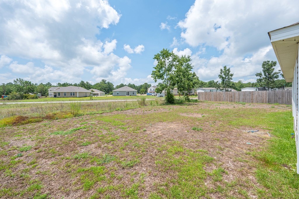 a yard with a fence and some houses in the background