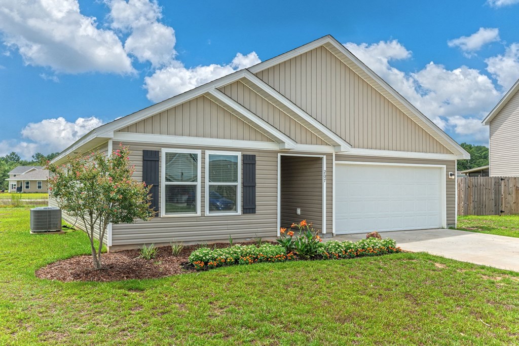 the front of a house with a lawn and a tree